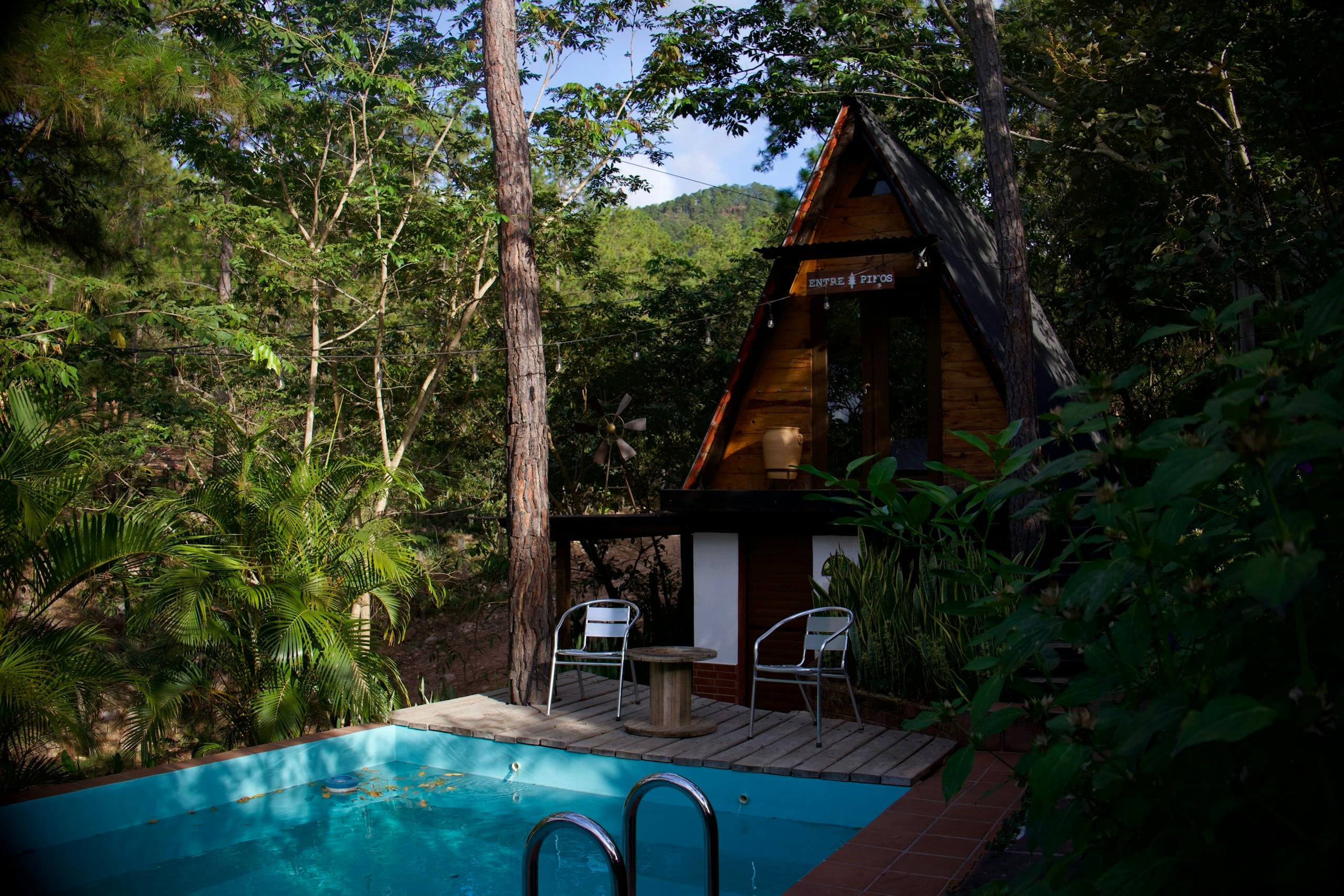 A-frame cabin with a small pool in a forest setting